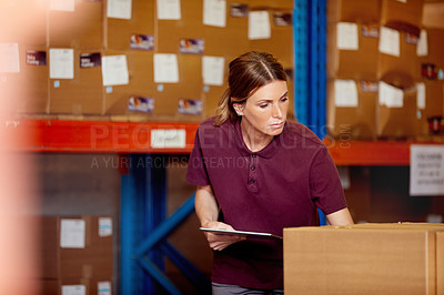 Buy stock photo Shot of a young woman using a digital tablet in a warehouse