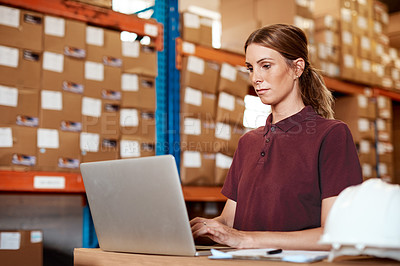 Buy stock photo Shot of a young woman using a laptop in a warehouse