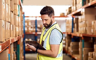 Buy stock photo Shot of a young man using a clipboard while working in a warehouse