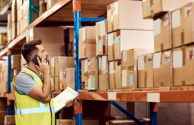 Buy stock photo Shot of a young man talking on a cellphone while working in a warehouse