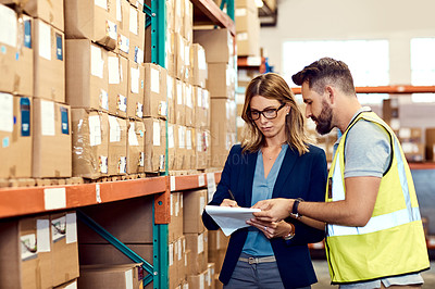 Buy stock photo Shot of a young man and woman working together in a warehouse