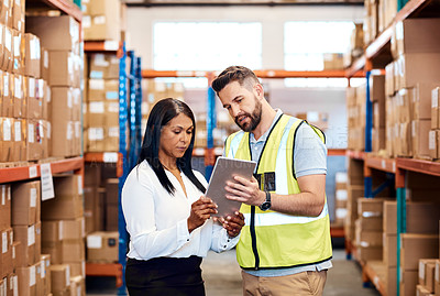 Buy stock photo Shot of a man and a woman using a digital tablet together in a warehouse