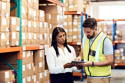 Buy stock photo Shot of a man and a woman using a digital tablet while working together in a warehouse