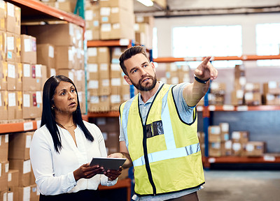 Buy stock photo Shot of a man and a woman using a digital tablet while working together in a warehouse
