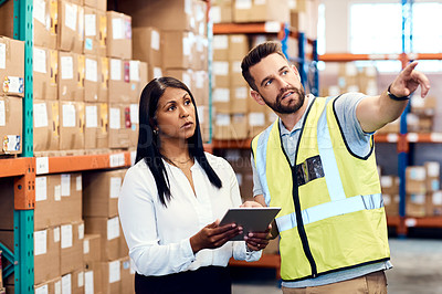 Buy stock photo Shot of a man and a woman using a digital tablet while working together in a warehouse