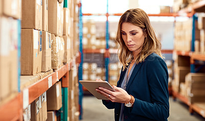 Buy stock photo Shot of a young factory manager using a digital tablet in a warehouse