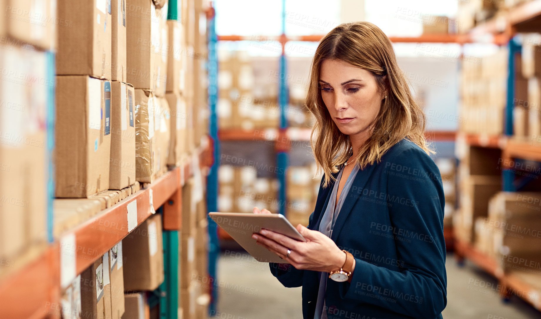 Buy stock photo Shot of a young factory manager using a digital tablet in a warehouse
