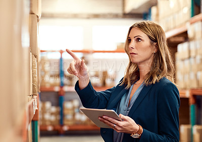 Buy stock photo Shot of a young factory manager using a digital tablet in a warehouse