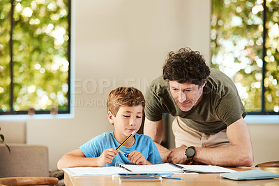 Buy stock photo Shot of a cute little boy doing homework with his father at home