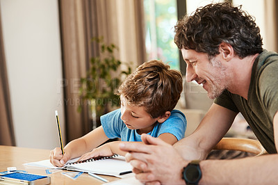 Buy stock photo Shot of a cute little boy doing homework with his father at home