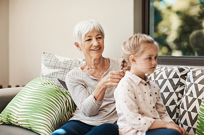 Buy stock photo Shot of a senior woman braiding her granddaughter’s hair outside at home