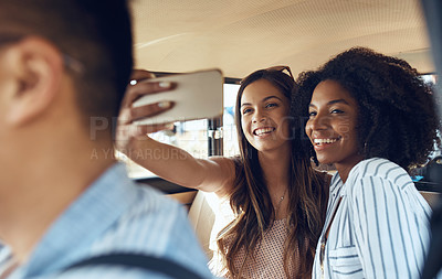 Buy stock photo Shot of a group of happy young friends taking selfies during a road trip
