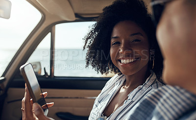 Buy stock photo Shot of a happy young couple using a smartphone on a road trip