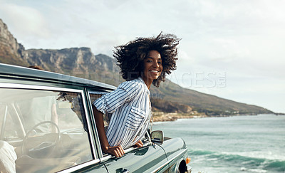 Buy stock photo Shot of a happy young woman leaning out of a car window on a road trip