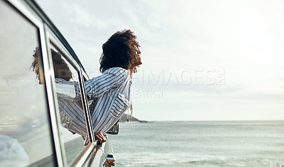Buy stock photo Shot of a happy young woman leaning out of a car window on a road trip