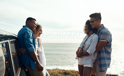 Buy stock photo Shot of a group of happy young friends enjoying a road trip along the coast