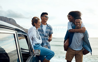 Buy stock photo Shot of a group of happy young friends having fun on a road trip along the coast
