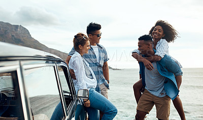 Buy stock photo Shot of a group of happy young friends having fun on a road trip along the coast