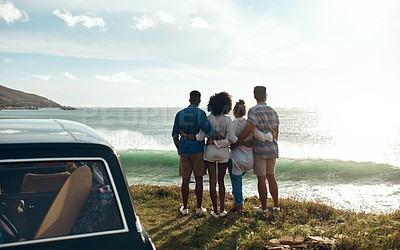 Buy stock photo Shot of a group of young friends watching the sunset on a road trip along the coast