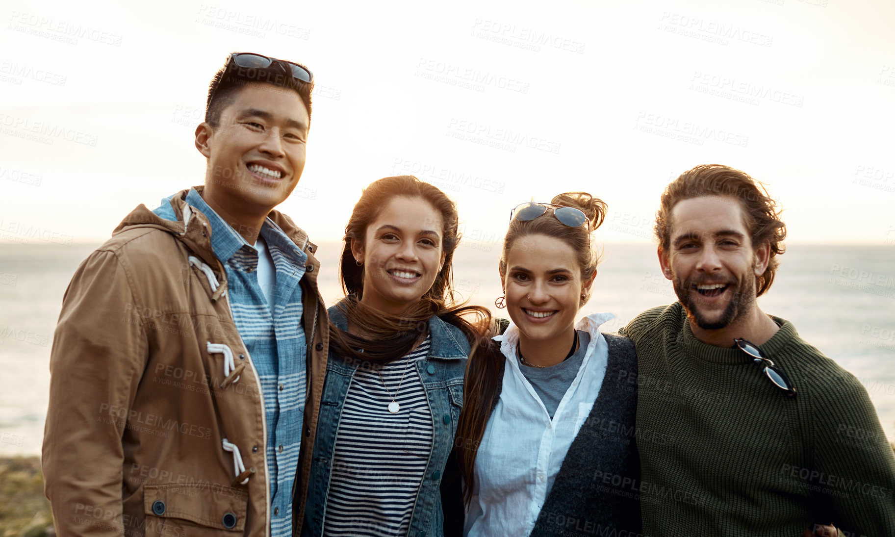 Buy stock photo Shot of a group of happy young friends enjoying a vacation along the coast