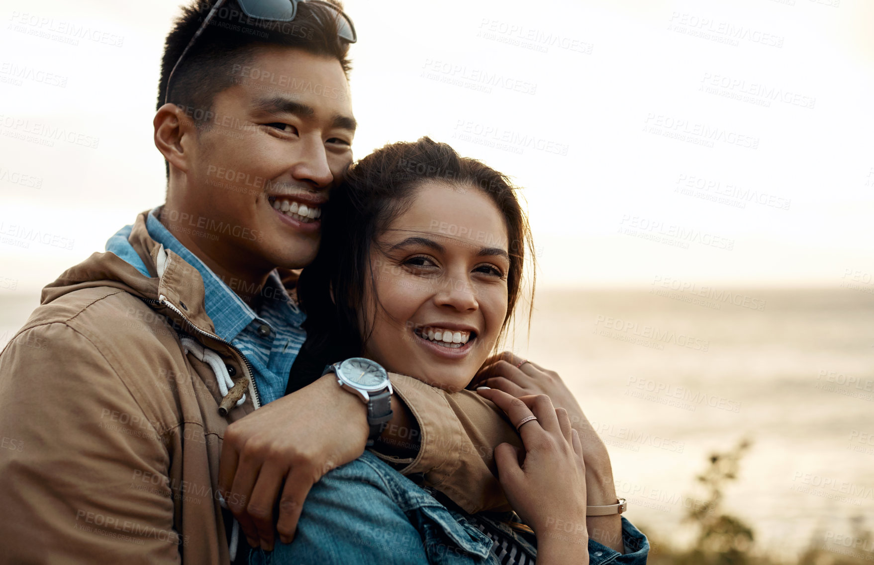Buy stock photo Couple, hug and connection by ocean for relationship, happy and bonding on holiday for anniversary. Love, portrait and interracial people with support, commitment and travel with milestone trip