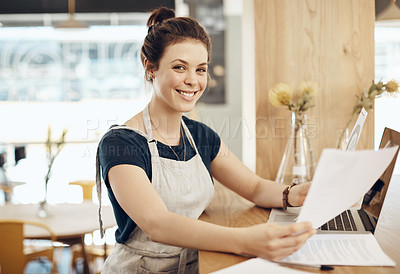 Buy stock photo Shot of a young cafe owner using her laptop and doing paperwork in her shop