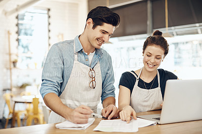 Buy stock photo Shot of two cafe owners having a discussion while using a laptop in their shop