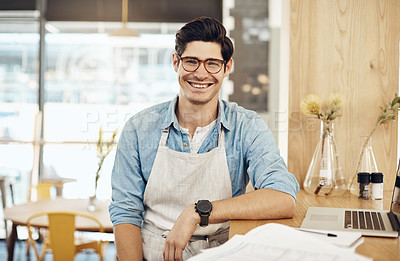 Buy stock photo Shot of a young cafe owner using his laptop and doing paperwork in his shop