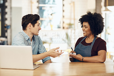 Buy stock photo Shot of a young waitress taking her customer's order in a cafe