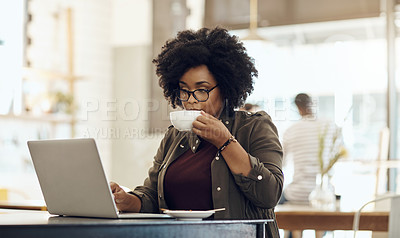Buy stock photo Cropped shot of a young woman enjoying a cup of coffee while using her laptop in a cafe