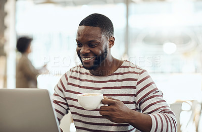 Buy stock photo Cropped shot of a young man enjoying a cup of coffee while using his laptop in a cafe