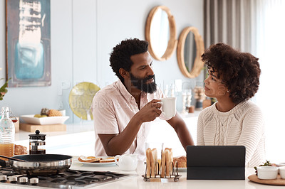 Buy stock photo Shot of a couple using a digital tablet while having breakfast at home