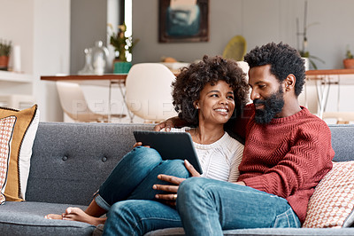 Buy stock photo Shot of an affectionate couple using a digital tablet while relaxing on the sofa at home