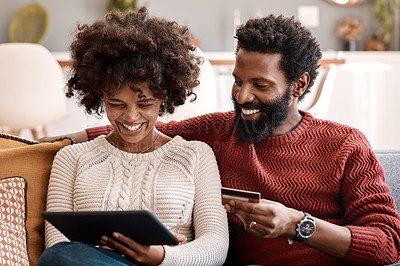 Buy stock photo Shot of a man holding a credit card while browsing on a digital tablet with his wife