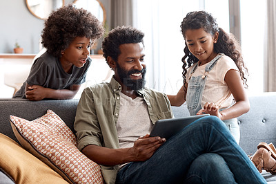 Buy stock photo Shot of a happy father using a digital tablet while bonding and relaxing with his two young children at home