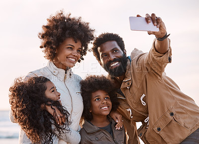 Buy stock photo Shot of a happy young family taking a selfie with a smartphone at the beach