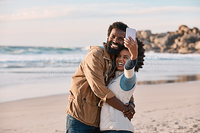 Buy stock photo Shot of a happy young couple taking selfies with a smartphone at the beach