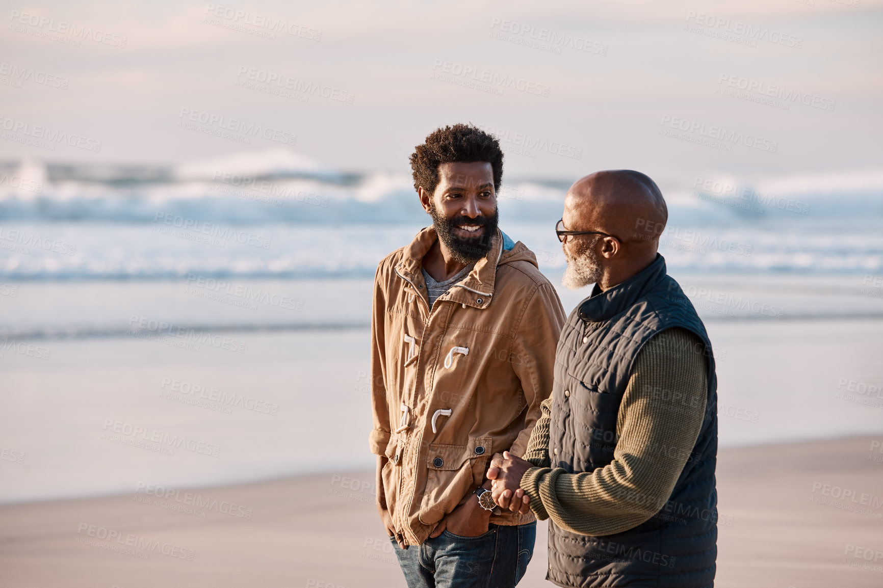 Buy stock photo Mature, dad and beach with adult son for bonding, walk or quality time for fathers day with smile. Space, conversation or healthy relationship with stroll on coast, together and black men in family