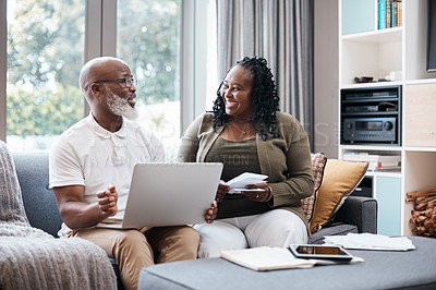 Buy stock photo Shot of a mature couple using a laptop while going through paperwork together at home
