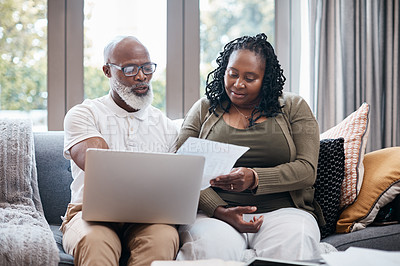 Buy stock photo Shot of a mature couple using a laptop while going through paperwork together at home