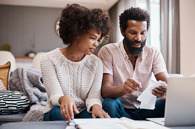 Buy stock photo Shot of a couple looking at paperwork while using a laptop in their living room