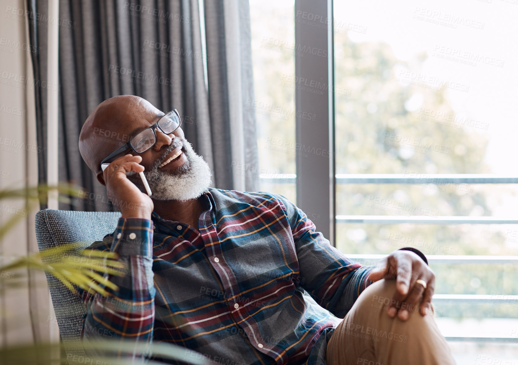 Buy stock photo Shot of a mature man talking on a cellphone while relaxing on a sofa at home