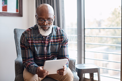 Buy stock photo Shot of a mature man using a digital tablet at home