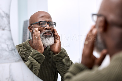 Buy stock photo Shot of a mature man examining his face in the bathroom at home