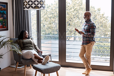 Buy stock photo Shot of a mature man using a digital tablet while talking to his wife at home