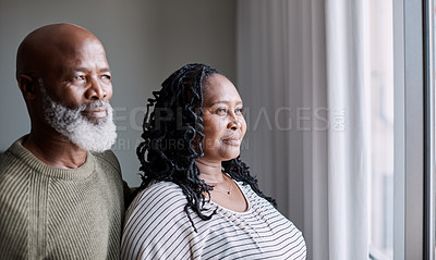 Buy stock photo Shot of a mature couple looking thoughtfully through a window at home