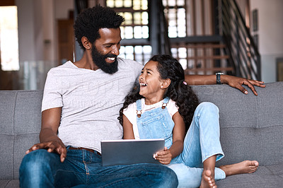 Buy stock photo Shot of an adorable little girl using a digital tablet while bonding and spending time with her father at home