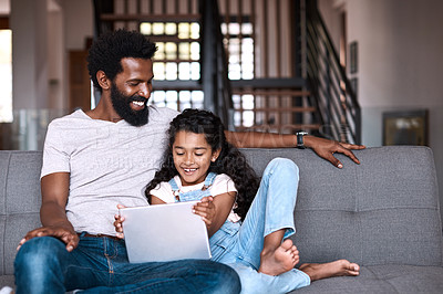 Buy stock photo Shot of an adorable little girl using a digital tablet while bonding and spending time with her father at home