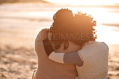 Buy stock photo Rearview shot of a young woman embracing her mother while watching the sunset at the beach