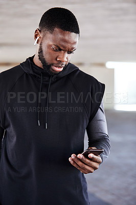 Buy stock photo Cropped shot of a handsome young male athlete checking his phone while working out in the city